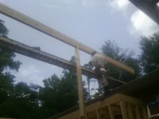 Carpenter setting a ridge beam over a new addition frame — Ice Dam Removal by Roofing Brothers in Darwin