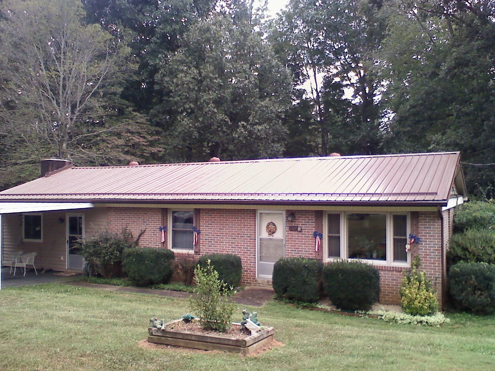 Bronze metal roof on a brick ranch home with a carport in Darwin