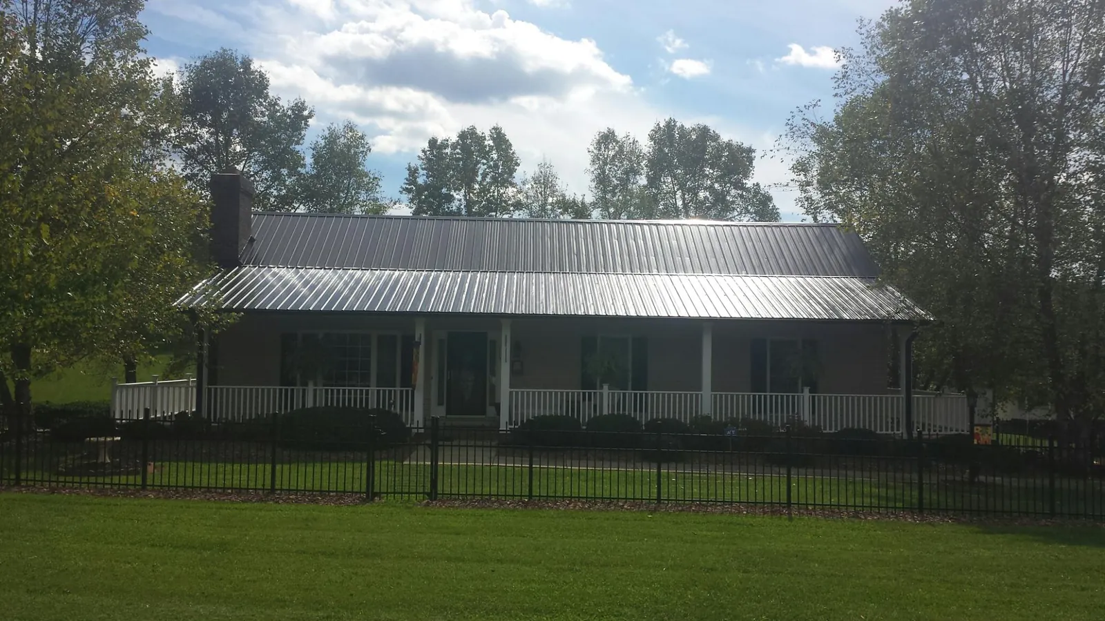 Gray metal roof on a brick ranch with a full width front porch — Gutter Guard Installation work by our crew in Darwin