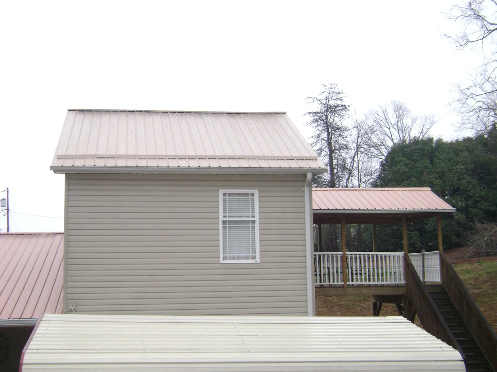 Tan metal roofs on a two story addition and attached porch, from a Roof Replacement job in Darwin